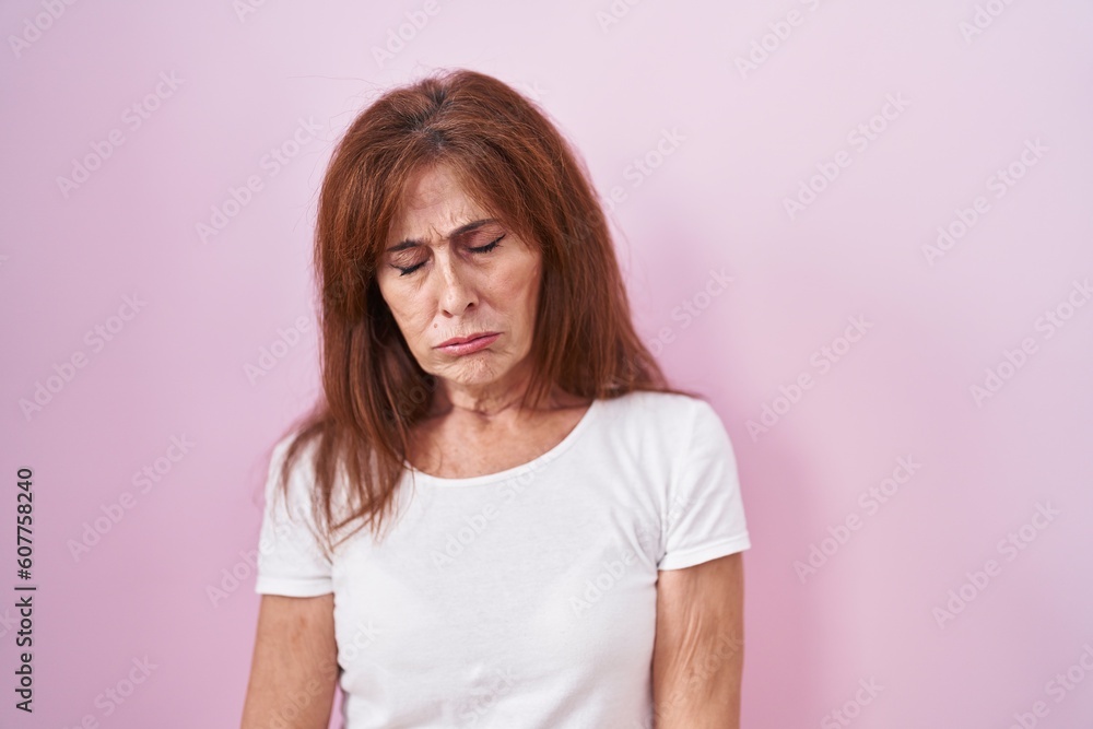 Middle age woman standing over pink background looking sleepy and tired, exhausted for fatigue and hangover, lazy eyes in the morning. Middle age woman standing over pink background looking sleepy and tired, exhausted for fatigue and hangover, lazy eyes in the morning.