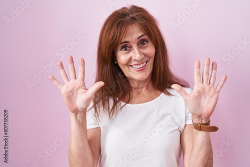 Wallpaper Mural Middle age woman standing over pink background showing and pointing up with fingers number ten while smiling confident and happy. Torontodigital.ca