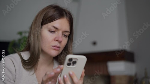 Closeup young beautiful Caucasian woman dialing phone number on touchscreen waiting for answer. Close-up slim confident lady calling on smartphone sitting at home indoors