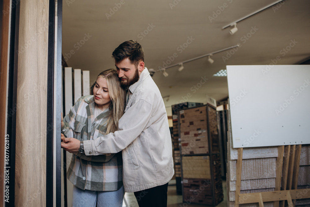 Fototapeta premium Beautiful young couple choosing ceramic tiles for their house repairment in the building shop.