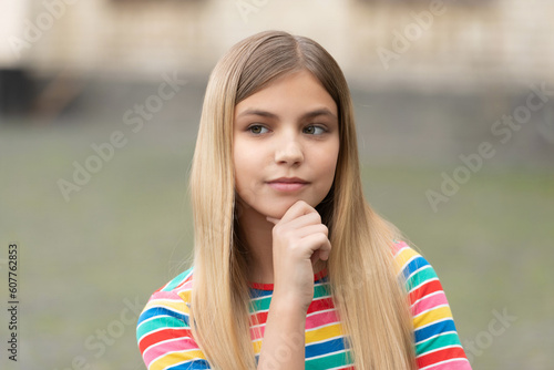 portrait of pondering teen girl with blonde hair. portrait of teen girl outdoor.