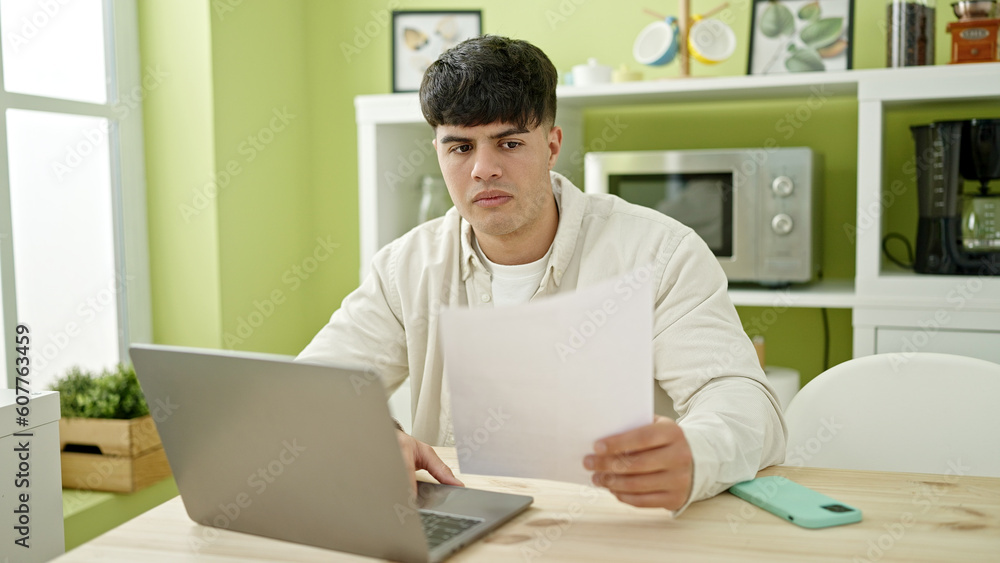Young hispanic man using laptop reading document at dinning room Young hispanic man using laptop reading document at dinning room