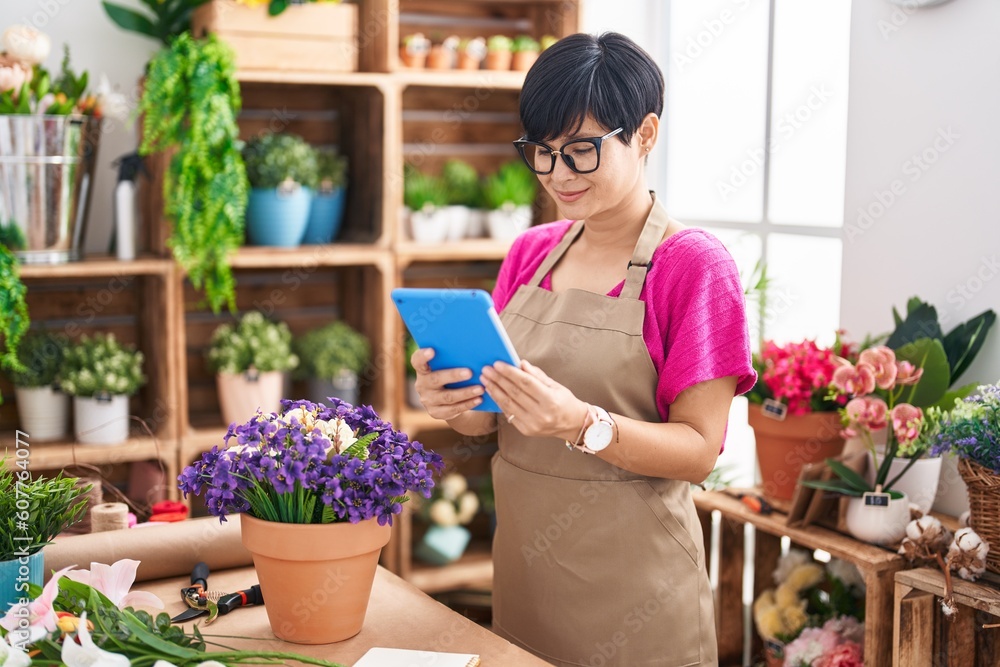 Middle age chinese woman florist smiling confident using touchpad at flower shop