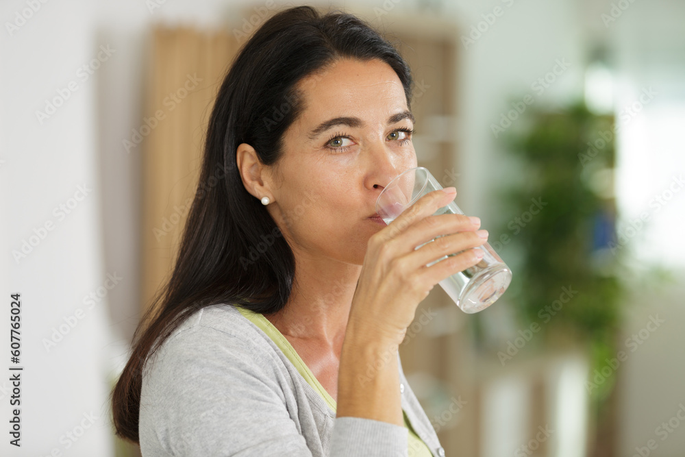 mature woman drinking water from glass isolated on grey