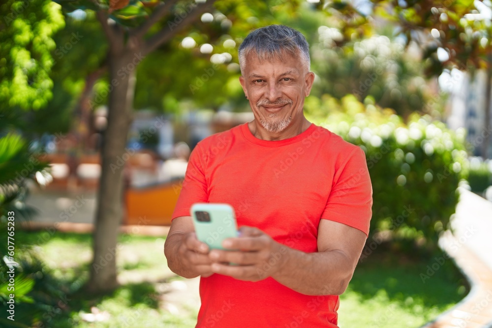 Middle age grey-haired man smiling confident using smartphone at park Middle age grey-haired man smiling confident using smartphone at park