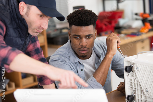 Canvas Print apprentice repairing an appliance under supervision