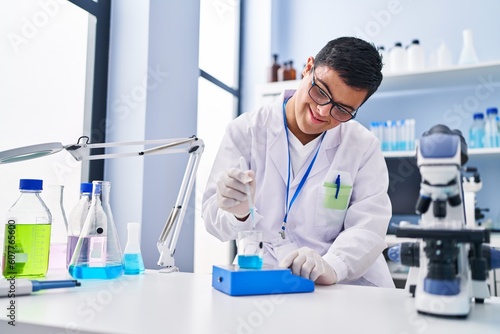 Down syndrome man wearing scientist uniform measuring liquid at laboratory