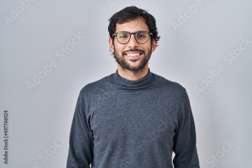 Handsome latin man standing over isolated background with a happy and cool smile on face. lucky person. © Krakenimages.com
