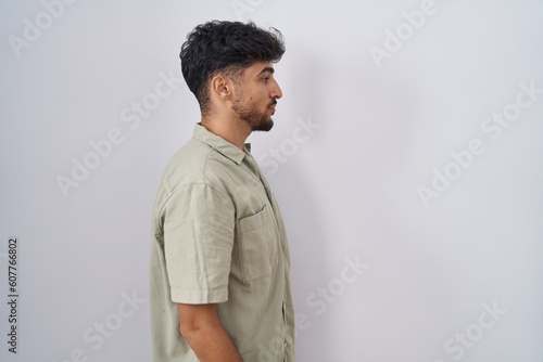 Arab man with beard standing over white background looking to side, relax profile pose with natural face and confident smile. © Krakenimages.com
