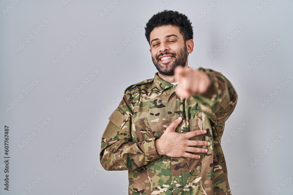 Arab man wearing camouflage army uniform laughing at you, pointing finger to the camera with hand over body, shame expression Arab man wearing camouflage army uniform laughing at you, pointing finger to the camera with hand over body, shame expression