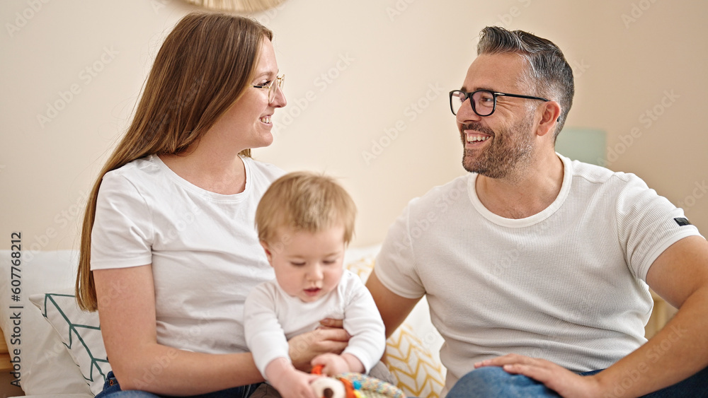 Family of mother, father and baby together sitting on the bed at bedroom Family of mother, father and baby together sitting on the bed at bedroom