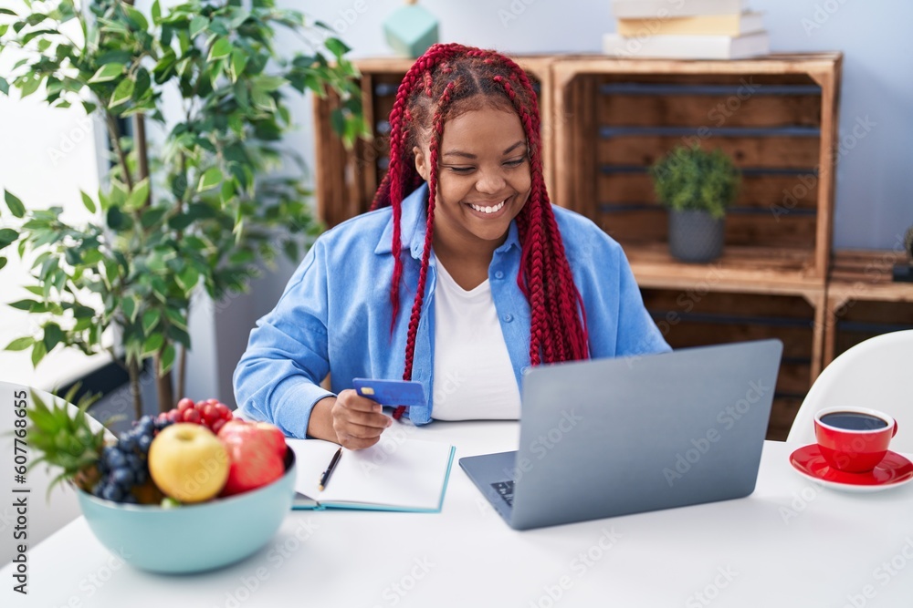 African american woman using laptop and holding credit card at home African american woman using laptop and holding credit card at home