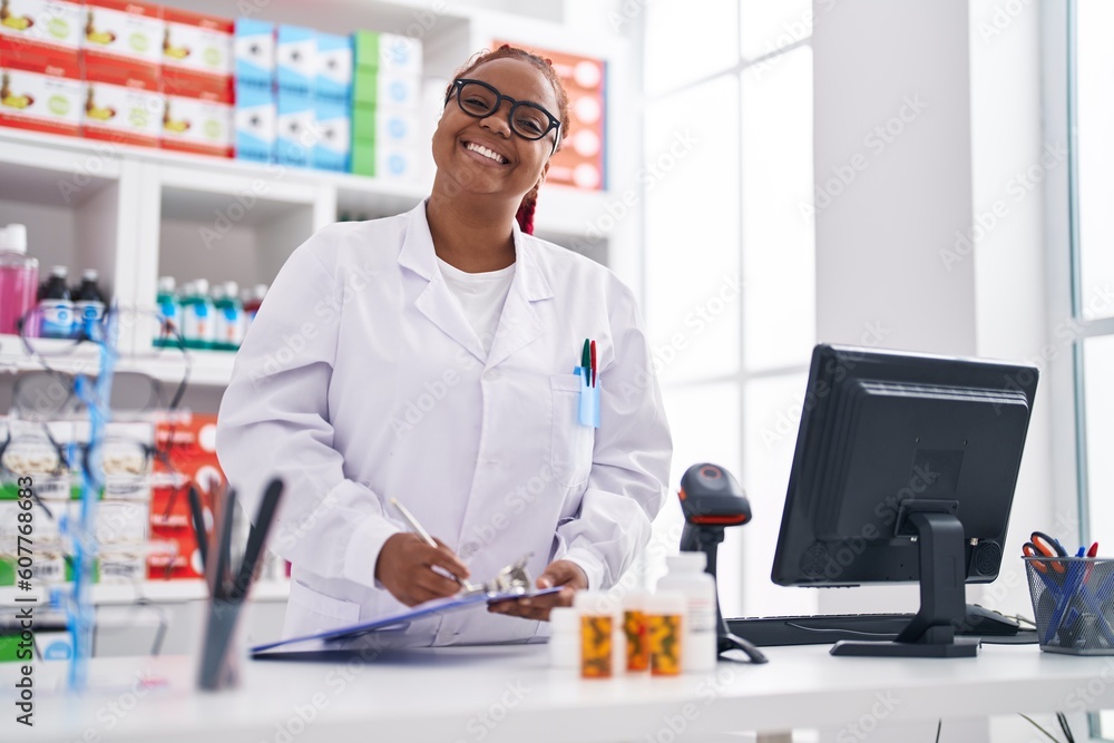 Obraz premium African american woman pharmacist writing on checklist at pharmacy
