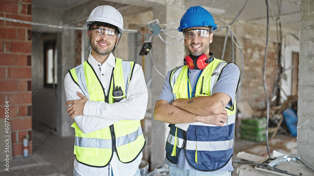 Two men builders smiling confident standing with arms crossed gesture at construction site Two men builders smiling confident standing with arms crossed gesture at construction site