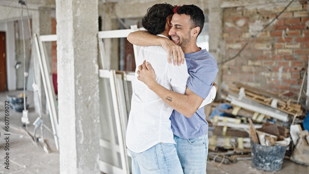Two men couple smiling confident hugging each other at construction site Two men couple smiling confident hugging each other at construction site