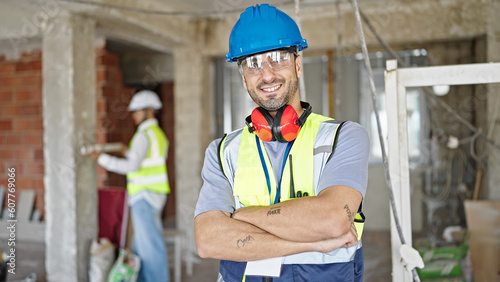 Two men builders standing with arms crossed gesture working at construction site