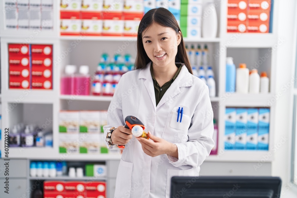 Chinese woman pharmacist scanning pills bottle at pharmacy