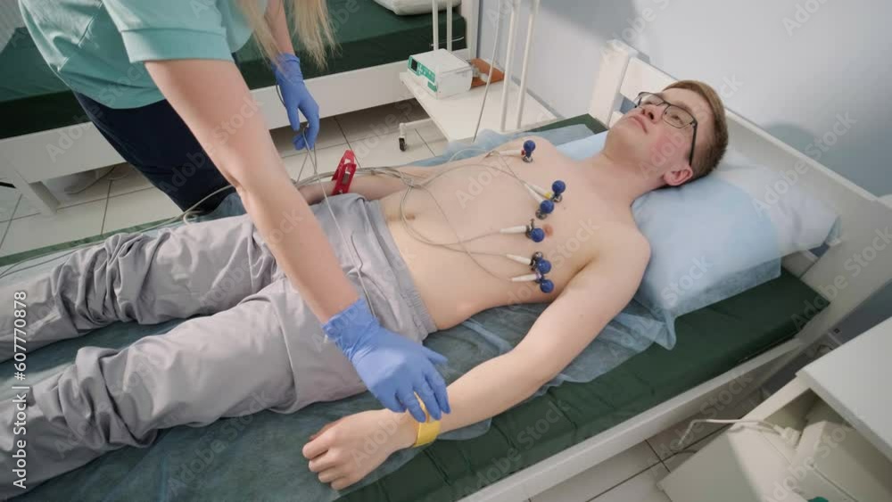 Cardiac examination in a hospital with a professional cardiograph. The patient lies on a bed with connected sensors. Cardiac examination in a hospital with a professional cardiograph. The patient lies on a bed with connected sensors.