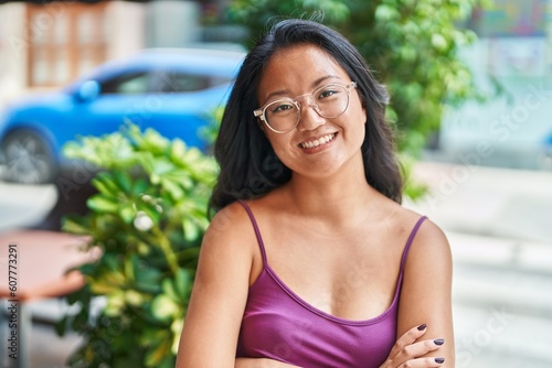 Young chinese woman standing with arms crossed gesture at coffee shop terrace Free Download Young chinese woman standing with arms crossed gesture at coffee shop terrace - GFXLoad