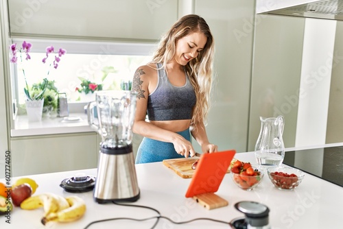 Young woman looking online juice recipe cutting apple at kitchen