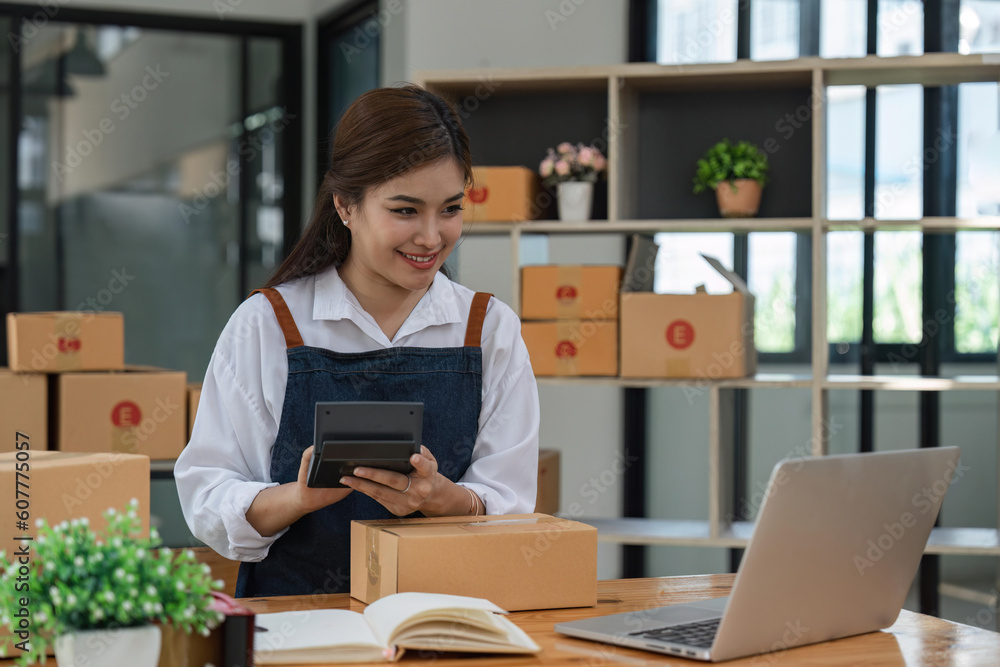 woman with Small business using calculator at workplace. Start up SME small business entrepreneurs working with boxes at home online selling ecommerce packing woman with Small business using calculator at workplace. Start up SME small business entrepreneurs working with boxes at home online selling ecommerce packing