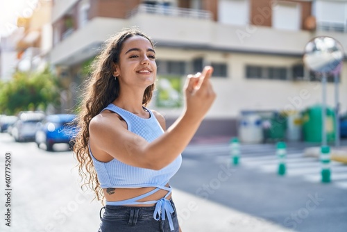 Young beautiful hispanic woman smiling confident doing coming gesture with finger at street