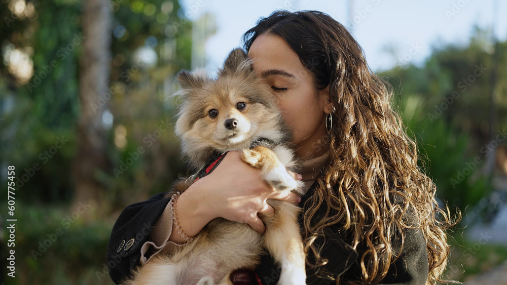 Young hispanic woman with dog standing kissing at park Young hispanic woman with dog standing kissing at park