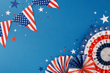 Concept of July 4th jubilation in the United States. Top view flat lay of american flag garlands, paper pinwheels, star-shaped confetti on blue background with empty space for text or advert