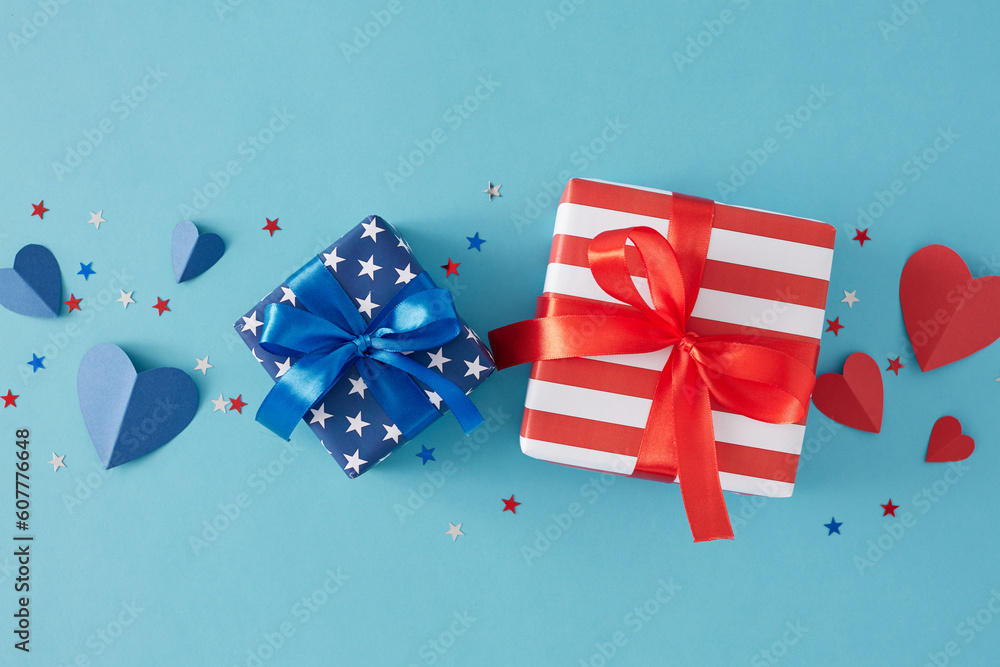 Fototapeta premium July 4th celebration theme concept. Top view flat lay of gift boxes with ribbon, blue and red hearts, star-shaped confetti on light blue background