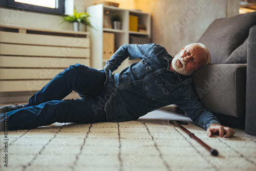 A Disabled Retiree with Walking Cane Fell on the Floor of the Living Room. Disabled Senior Man Lying On Carpet. Senior man in pain on the floor after a fall © Dragana Gordic