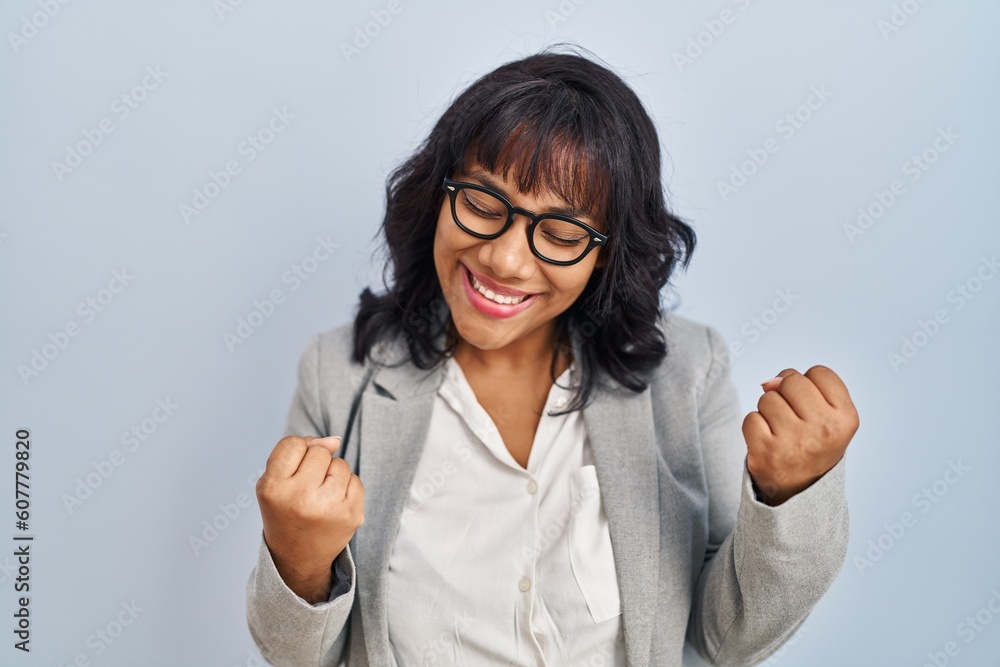 Hispanic woman standing over isolated background very happy and excited doing winner gesture with arms raised, smiling and screaming for success. celebration concept. Hispanic woman standing over isolated background very happy and excited doing winner gesture with arms raised, smiling and screaming for success. celebration concept.