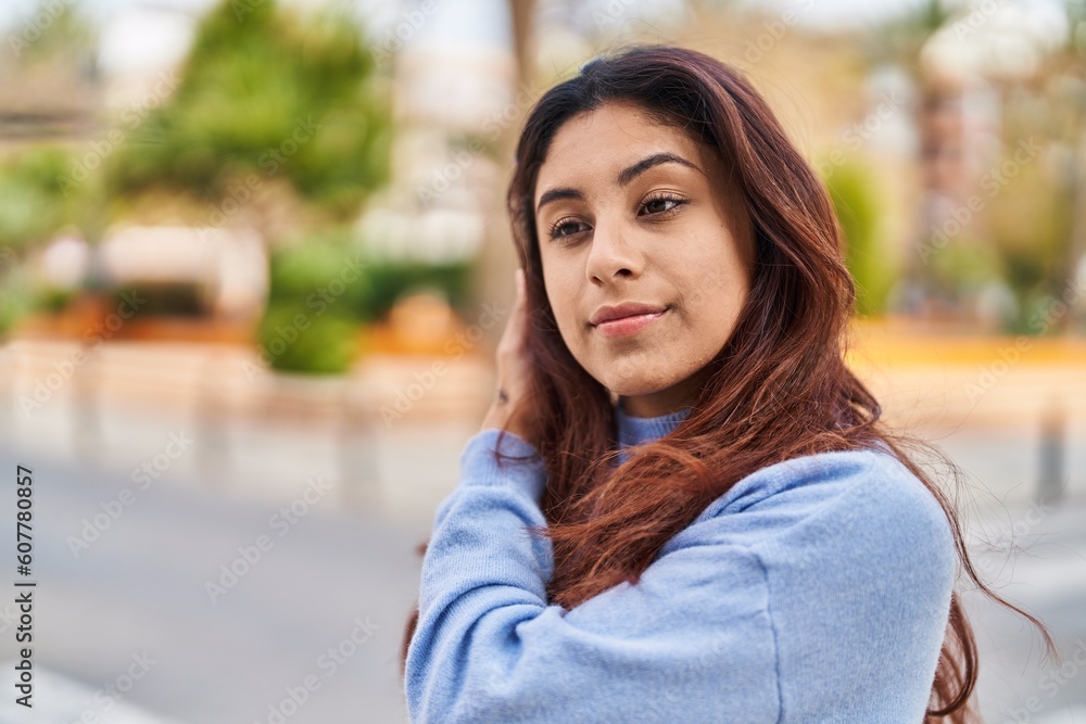 Young hispanic woman with relaxed expression standing at street