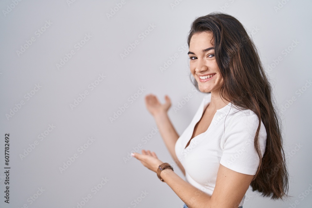 Young teenager girl standing over white background inviting to enter smiling natural with open hand Young teenager girl standing over white background inviting to enter smiling natural with open hand