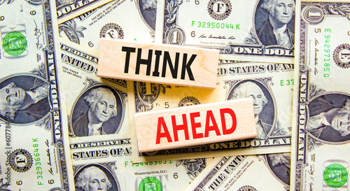 Think ahead symbol. Concept words Think ahead on wooden blocks on a beautiful background from dollar bills. Dollar bills. Business, support, motivation, psychological think ahead concept. Copy space.