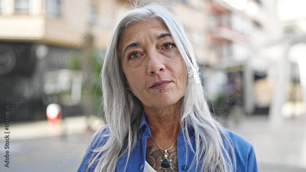 Middle age grey-haired woman standing with serious expression at street Middle age grey-haired woman standing with serious expression at street