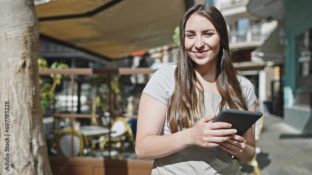 Young beautiful hispanic woman waitress smiling confident using touchpad at coffee shop terrace Young beautiful hispanic woman waitress smiling confident using touchpad at coffee shop terrace