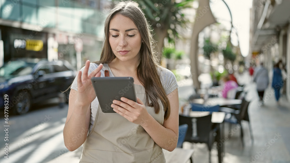 Young beautiful hispanic woman waitress using touchpad at coffee shop terrace Young beautiful hispanic woman waitress using touchpad at coffee shop terrace