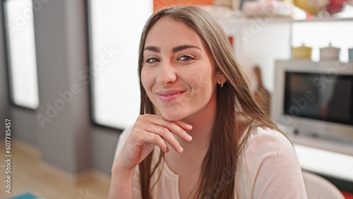 Young beautiful hispanic woman smiling confident sitting on table at dinning room