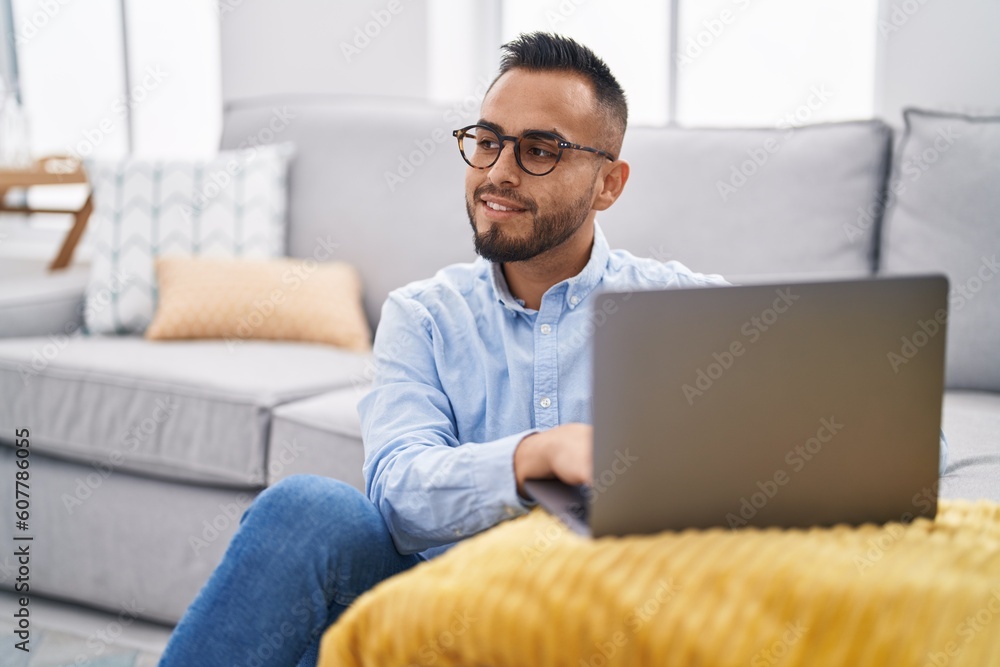 Young hispanic man using laptop sitting on floor at home Young hispanic man using laptop sitting on floor at home