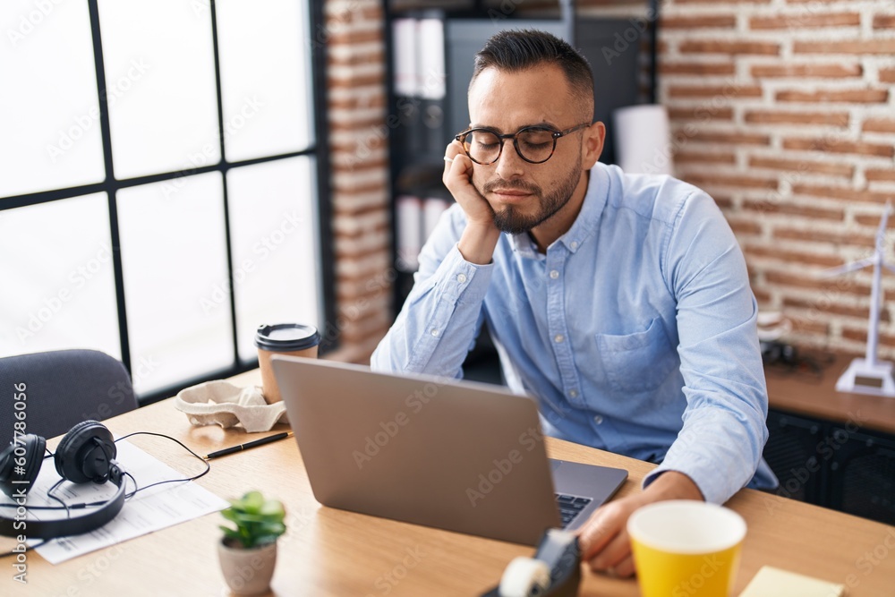 Young hispanic man business worker tired using laptop working at office Young hispanic man business worker tired using laptop working at office