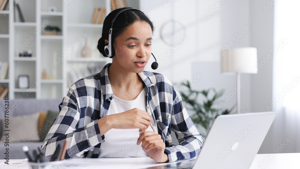 A young African American businesswoman in a headset communicates using video call. Ethnic female student talking while looking at laptop computer, online office conference, virtual learning concept. A young African American businesswoman in a headset communicates using video call. Ethnic female student talking while looking at laptop computer, online office conference, virtual learning concept.