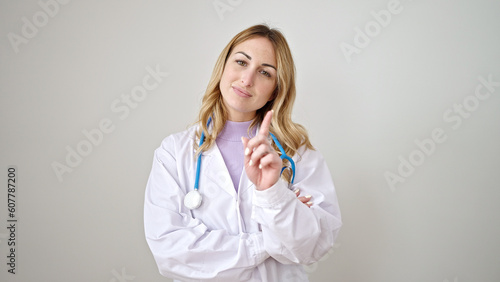 Young beautiful hispanic woman doctor standing with serious expression saying no with finger over isolated white background