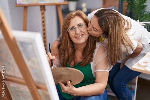 Mother and daughter artists hugging each other drawing and kissing at art studio