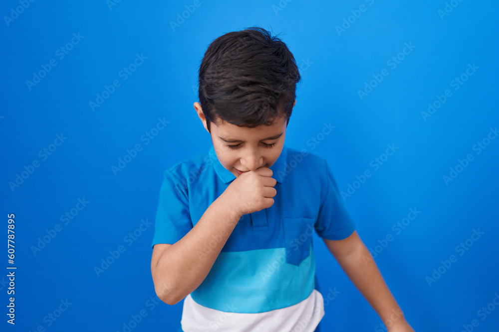 Little hispanic boy standing over blue background feeling unwell and coughing as symptom for cold or bronchitis. health care concept. Little hispanic boy standing over blue background feeling unwell and coughing as symptom for cold or bronchitis. health care concept.