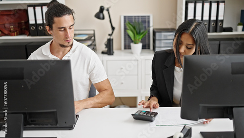 Man and woman business workers using computer and calculator at office