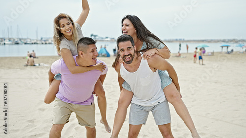 Group of people holding women on back playing at beach