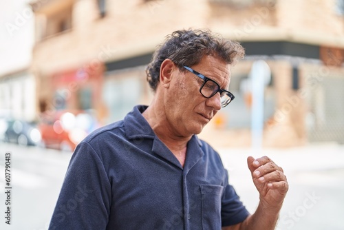 Middle age man standing with illness expression at street