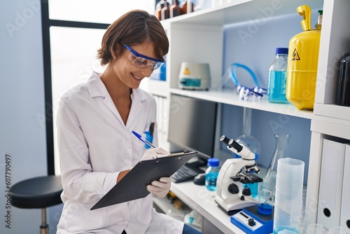 Wallpaper Mural Young beautiful hispanic woman scientist smiling confident writing report working at laboratory Torontodigital.ca
