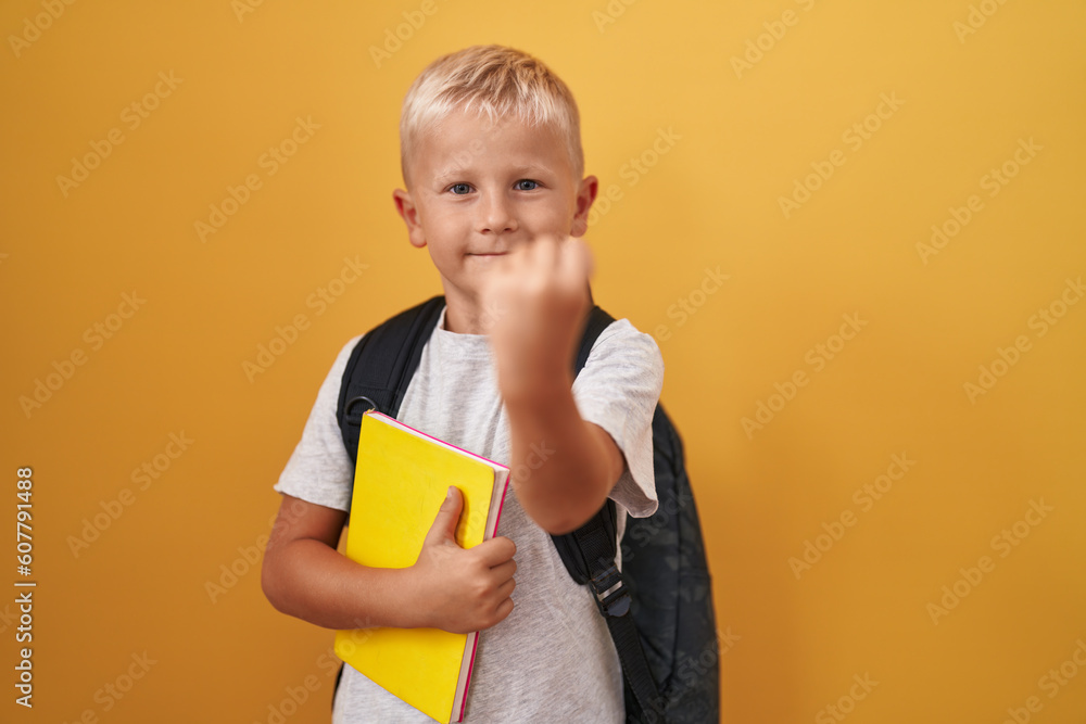 Little caucasian boy wearing student backpack and holding book annoyed and frustrated shouting with anger, yelling crazy with anger and hand raised Little caucasian boy wearing student backpack and holding book annoyed and frustrated shouting with anger, yelling crazy with anger and hand raised