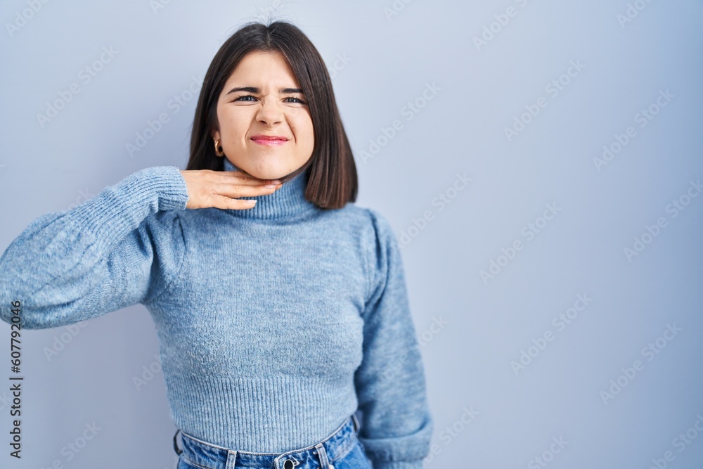 Young hispanic woman standing over blue background cutting throat with hand as knife, threaten aggression with furious violence Young hispanic woman standing over blue background cutting throat with hand as knife, threaten aggression with furious violence